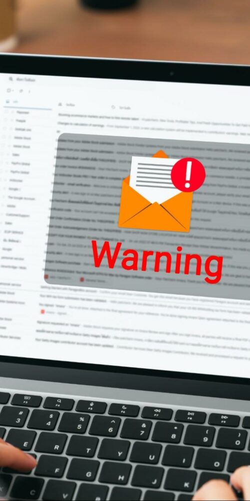 Employee reviewing email with phishing warning alert for payroll fraud prevention.