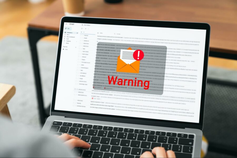 Employee reviewing email with phishing warning alert for payroll fraud prevention.